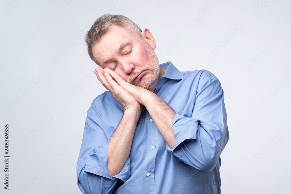 European man in blue shirt being tired sleeping on hands. European man in blue shirt being tired sleeping on hands.