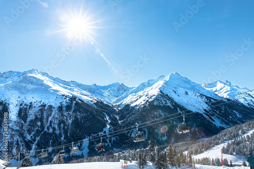 Young sporty man is skiing, doing winter sports in a winter paradise. Snow covered mountains, blue sky and colorful ski suit