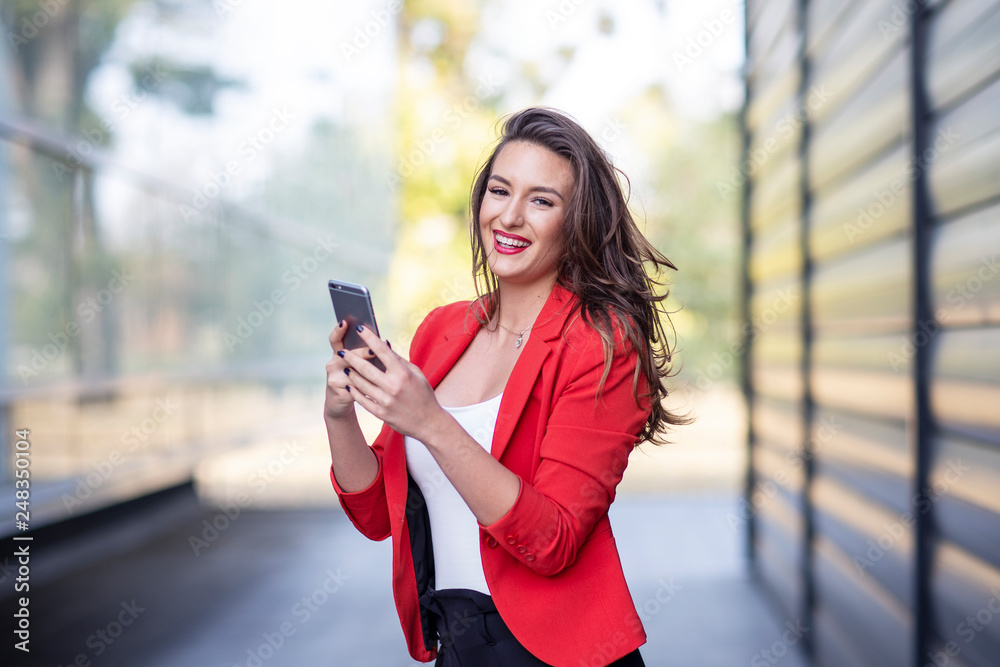 Long hair beautiful business woman in red suit reading text message on mobile phone Long hair beautiful business woman in red suit reading text message on mobile phone