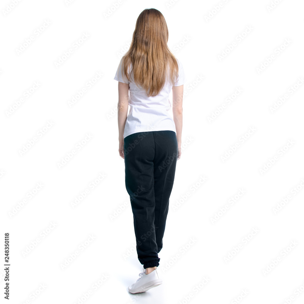 Woman in black sweatpants and white t-shirt walking goes on white background isolation, back view Woman in black sweatpants and white t-shirt walking goes on white background isolation, back view
