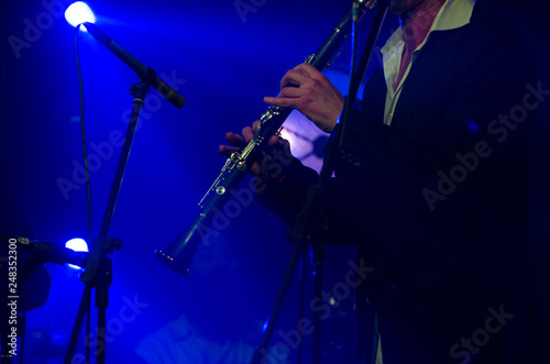 Artist, musician performing jazz with clarinet in the blue light, scene, performance concept