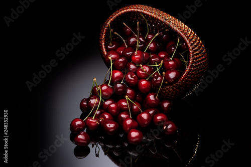 Fresh cherry in a wicker basket on a black background.