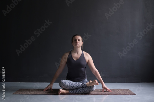 Womanl working out, doing yoga exercise on floor agnistambhasana photo