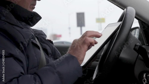 Adult Man Sits In The Modern Car And Works On Tablet