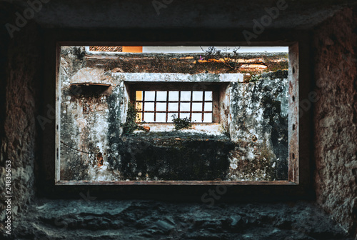 Foto The view from the dark desolate stone room through the window hole of an abandon