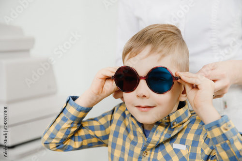 Ophthalmologist tests child kid boy color blindness, eye vision test photo