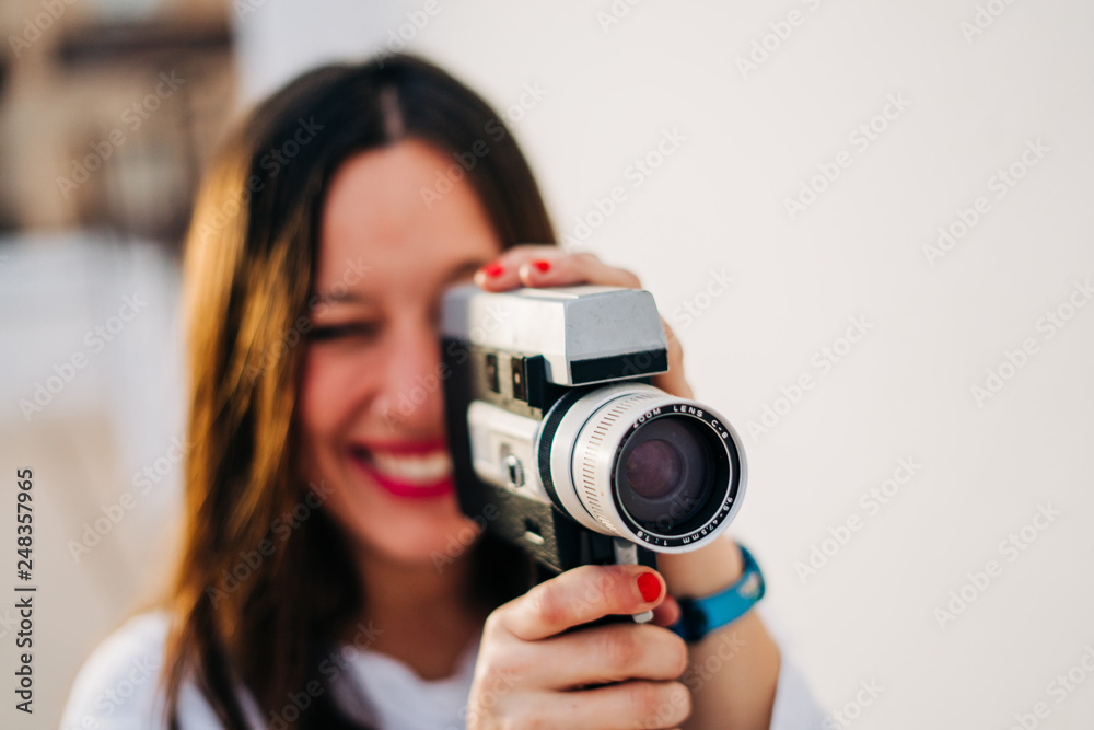 young smiling woman with red lips using a retro video camera isolated on a white background young smiling woman with red lips using a retro video camera isolated on a white background