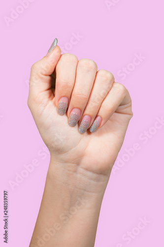 Closeup view of beautiful female hands with old silver sparkling manicure isolated on pink background. Woman needs correction. Vertical color photography.