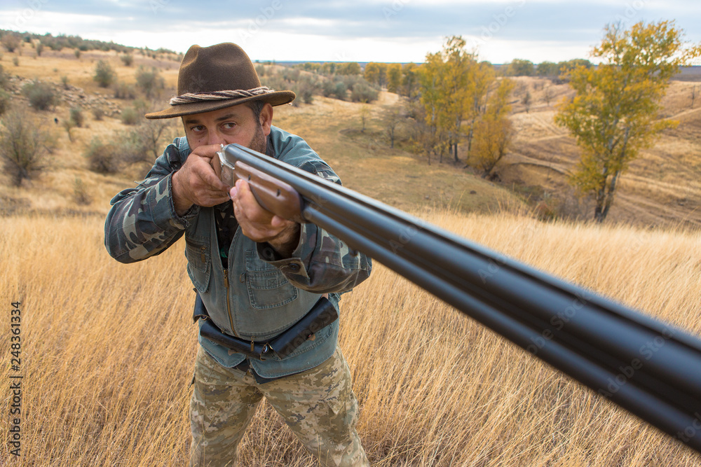 Fototapeta premium Hunter with a hat and a gun in search of prey in the steppe 
