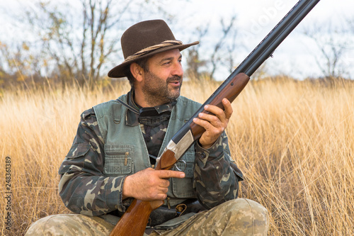 Hunter with a hat and a gun in search of prey in the steppe 