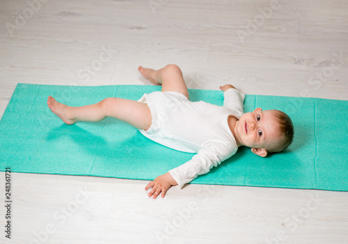 the baby is performing physical exercises on the yoga mat. Baby Yoga