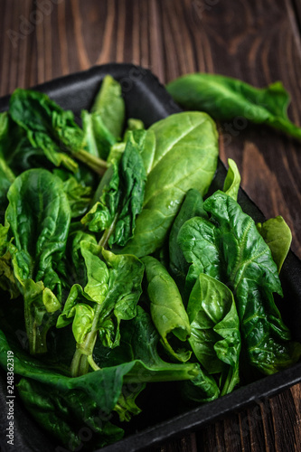 Leaves of spinach. Fresh organic spinach on a wooden table. Vegan food, healthy food. Dark rustic style photo.