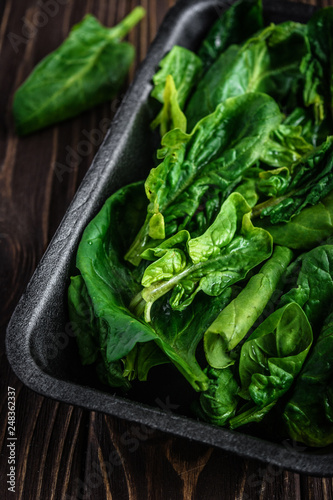 Leaves of spinach. Fresh organic spinach on a wooden table. Vegan food, healthy food. Dark rustic style photo.