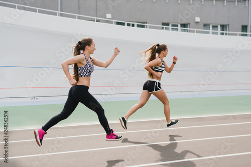 Running and fitness. Young beautiful fit women with perfect bodies in sportswear run outdoors on the track. Sportive and healthy lifestyle  working out  training  fashion  beauty concept.