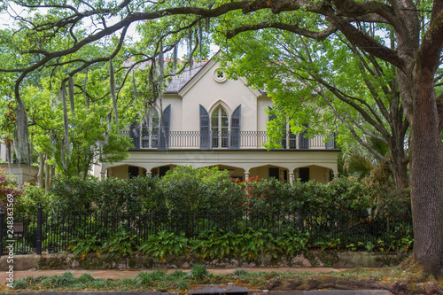 Mansion in Garden District of New Orleans, Louisiana, USA. Upper story windows are framed by branches of live southern oak tree with Spanish moss photo