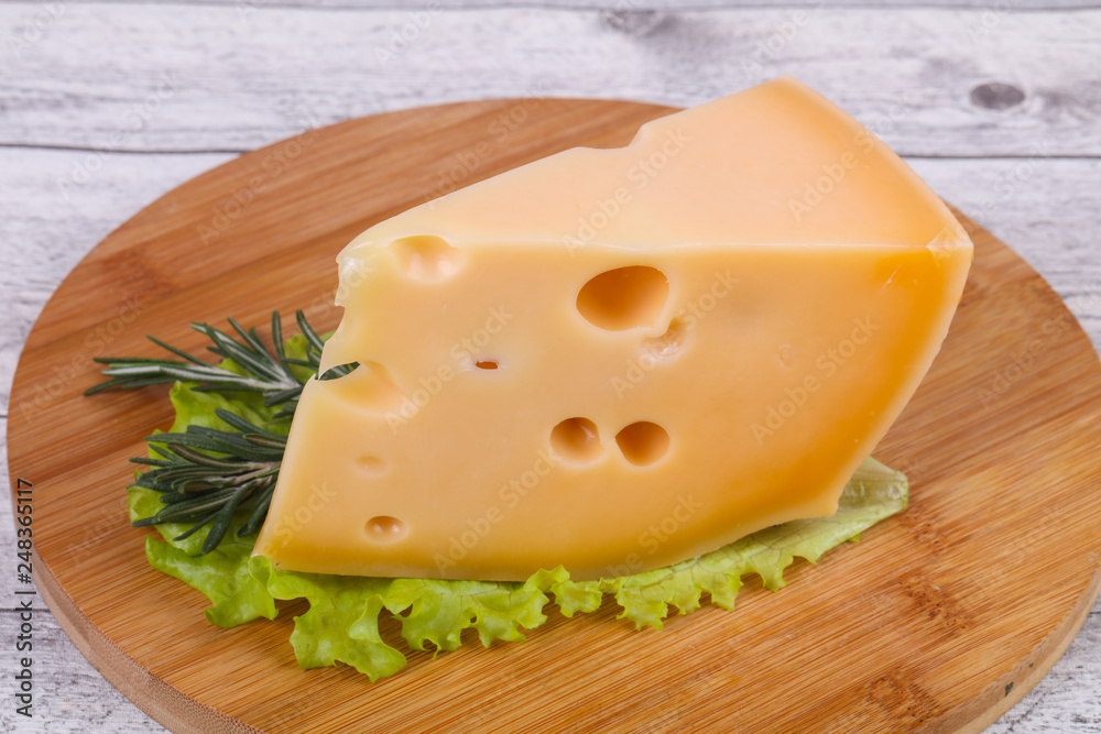 Maasdam cheese in the board served salad leaves Maasdam cheese in the board served salad leaves