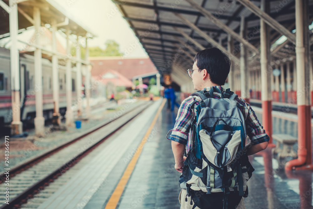 Young man asian with backpack at the train station. Travel concept.