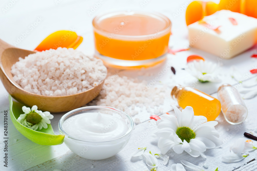 aromatherapy: orange gel and extract, bath salt, cosmetic cream, organic soap and petals on white wood aromatherapy: orange gel and extract, bath salt, cosmetic cream, organic soap and petals on white wood