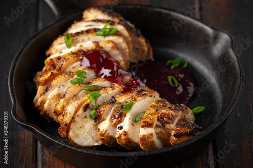 Grilled sliced chicken breast with cranberry sauce in mini cast iron frying pan