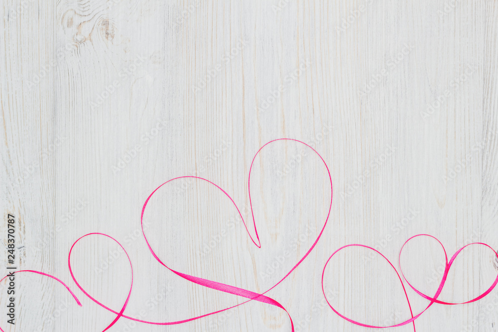 Red ribbon heart on wooden table. Flat lay. Valentine's Day celebration concept Red ribbon heart on wooden table. Flat lay. Valentine's Day celebration concept