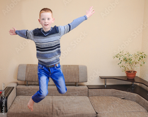Fototapeta Naklejka Na Ścianę i Meble -  Overjoyed boy jumping on couch at home shot with tilt and shift lens