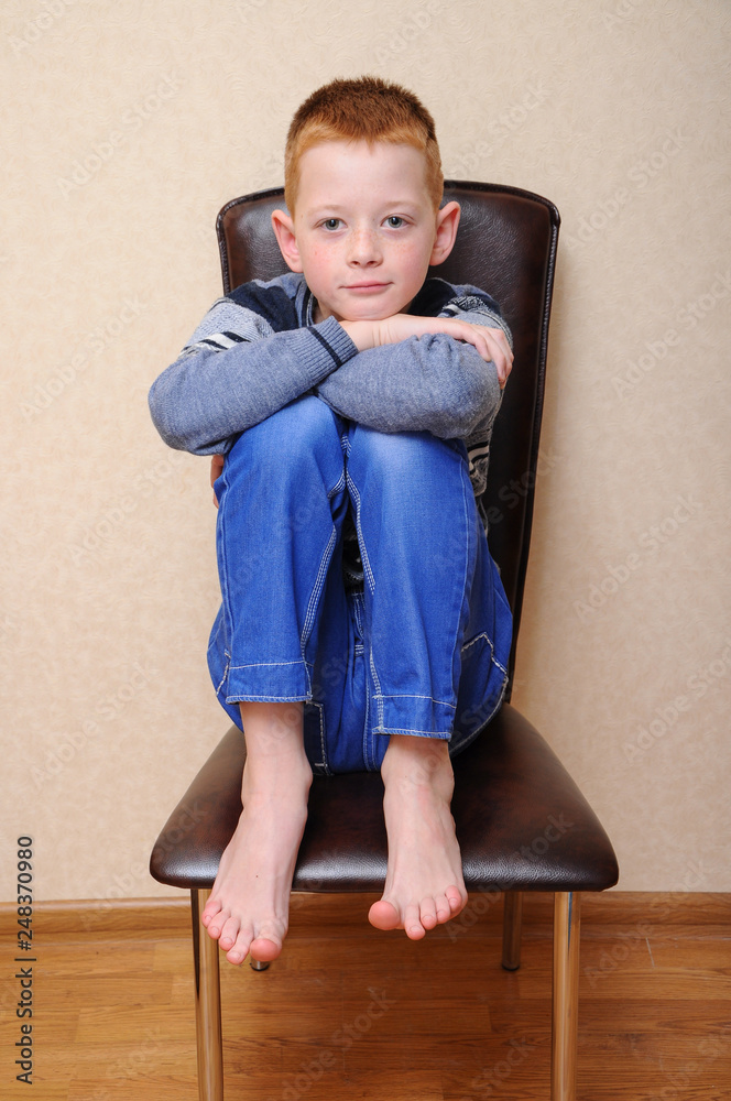 a young preteen boy sits on a chair a young preteen boy sits on a chair