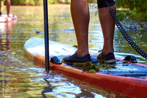 Men's legs on SUP (stand up paddle board) in water of the river