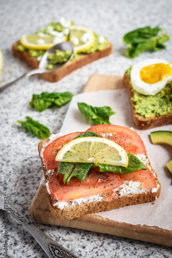 Healthy avocado and egg toasts. Toast, avocado, egg, tomatoes, spinach, cheese Feta, lemon. Organic healthy food. Clean healthy eating