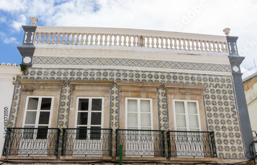 White wooden terrace doors with windows on it. Small balconies. Typical Portuguese tiles (azulejos) on the wall around the terrace.