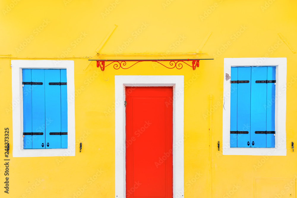 Yellow house with red Door in the village of Burano, Venice