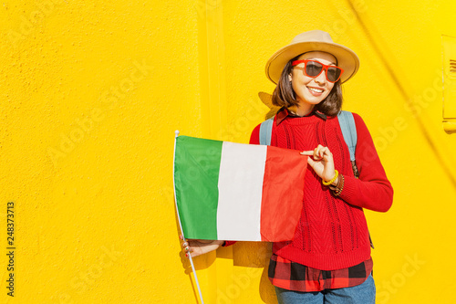 Young happy traveler with italian flag near famous colorful buildings, Tour and vacation in Italy concept
