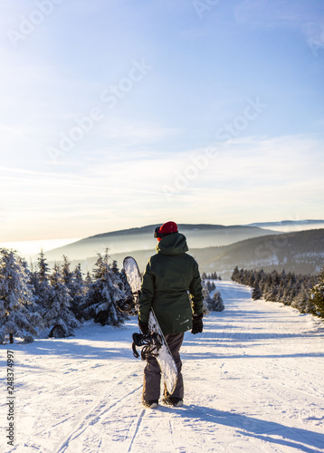 Back view of female snowboarder enjoying mountain landscape 