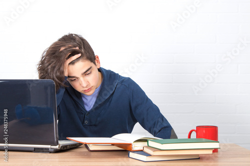 young man with computer and books on the desk studying