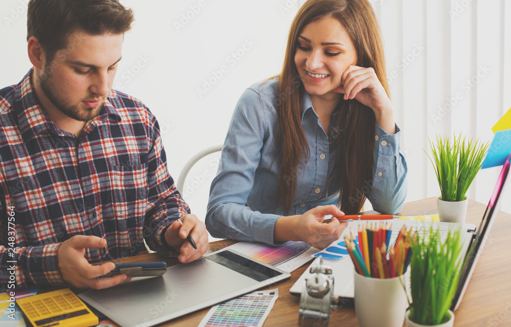 Obraz premium Two young creative designer colleagues using tablet at office