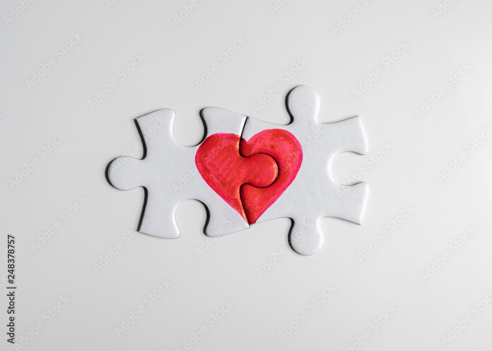 Love puzzle. Pieces of a puzzle with half of a red heart drawn on each  piece, fitting perfect together. Photos | Adobe Stock
