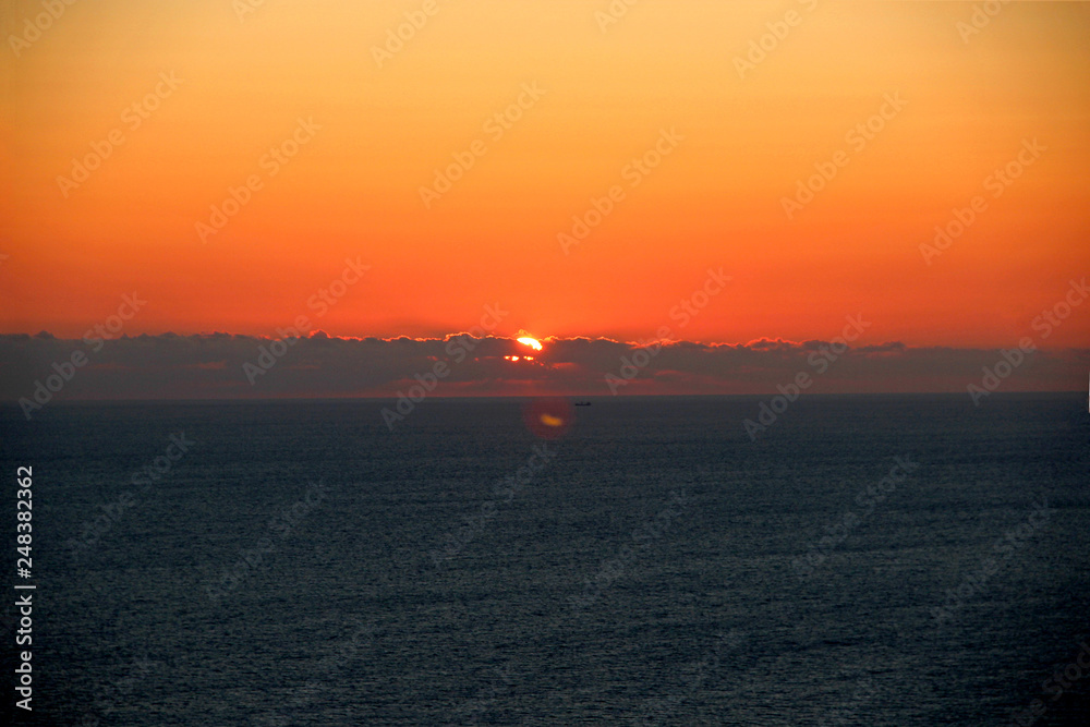 Fototapeta premium Beautiful sunset over the sea. The sun has a beautiful orange and red color.