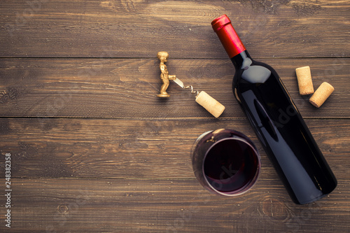 Glass bottle of wine with corks on wooden table background.Top view with copy space