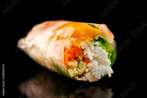 Closeup image of goi cuon spring rolls with shrimps, onion, mango, pork and noodles isolated at black background. Traditional vietnamese food.