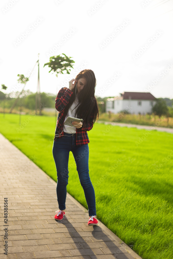 young brunette woman listen top chart song. Jump and dance on the grass