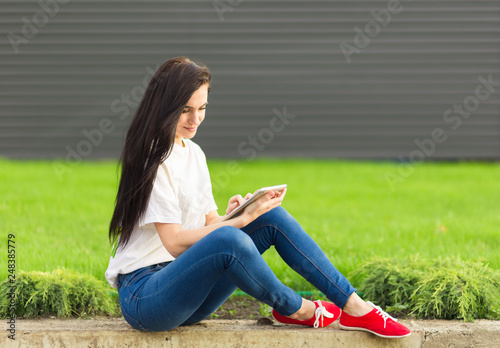 young brunette womanwith tablet serfing in internet on grass © klepach
