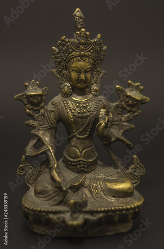 Tibetan Buddhism: Green Tara brass sculpture isolated on dark background.