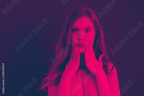 A girl holds her mouth with her hands pink and blue duotone