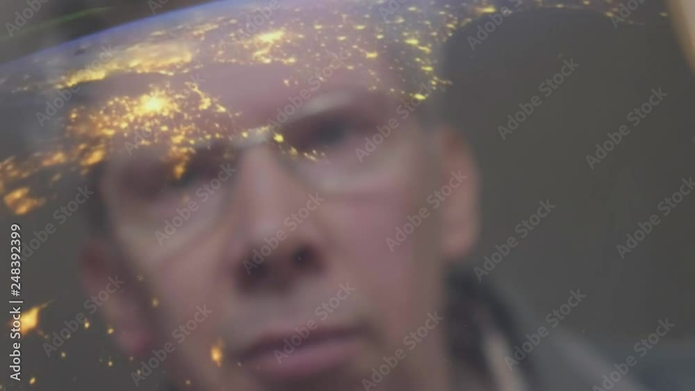 Reflection of a caucasian man looking at a view of the earth shot from the International Space station on a screen - Created with public domain footage from Nasa
