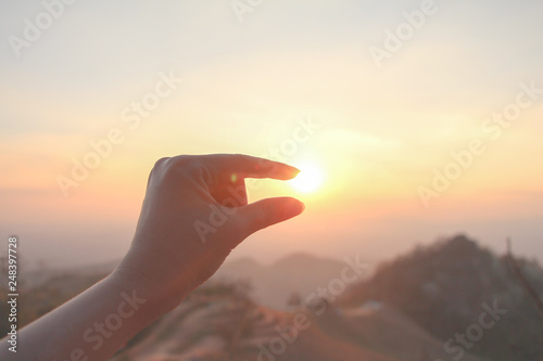 Hand up holding or catch the sun with beautiful nature sunset on mountain with vanilla sky as vacation.