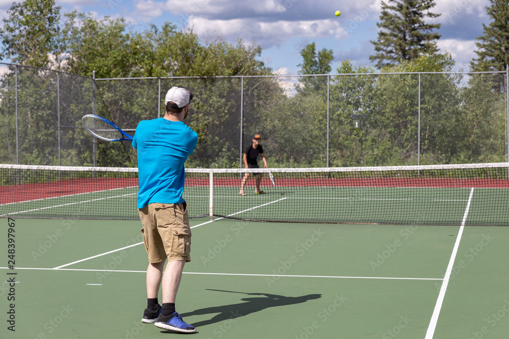 father and young son having tennis match on the courts