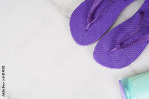 Close-up of a pair of flip-flops and sunscreen.