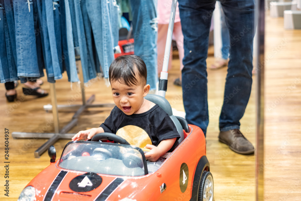 Little boy very enjoy sitting in big toy car, child enjoying shopping day with mother Little boy very enjoy sitting in big toy car, child enjoying shopping day with mother