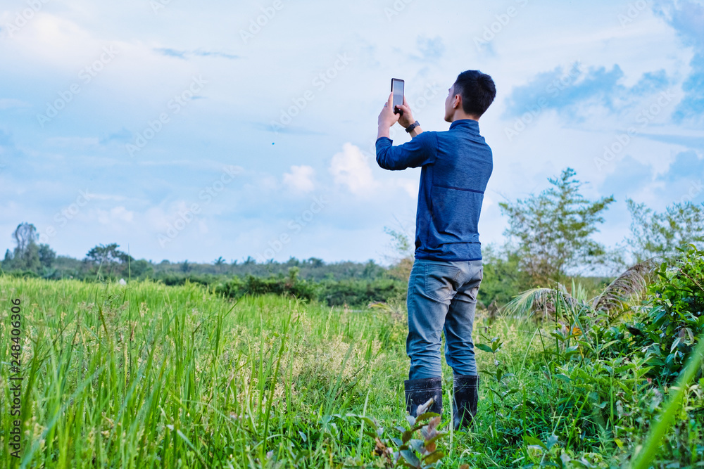 Young modern farmer using the mobile phone technology in agricultural field. Young modern farmer using the mobile phone technology in agricultural field.