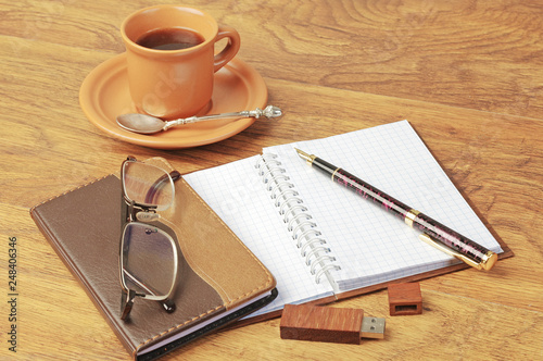 Notepad, fountain pen, glasses, cup of coffee.