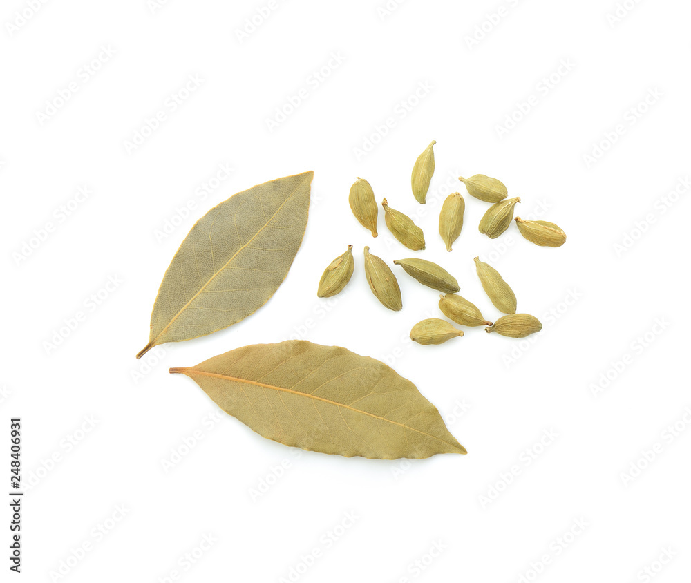 Green cardamom and bay leaves on white background